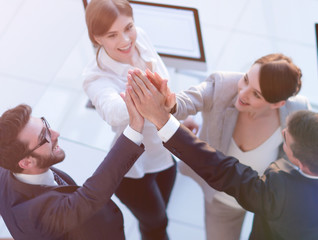 successful business team giving each other a high-five, standing in the office