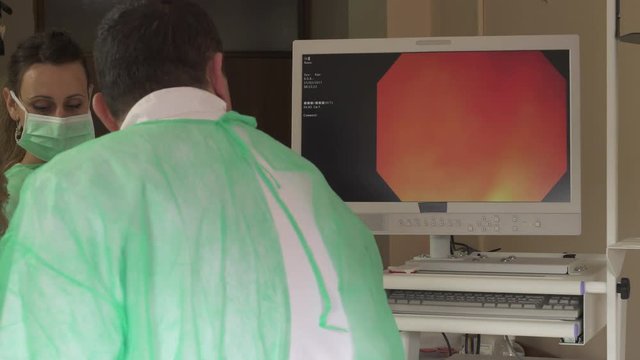 Gastroscopy examination. Gastroenterologist controls probe with micro camera for examining patient, doctor on computer monitor watching inside of stomach, nurses assisting doctor during medical review