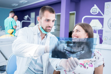 Doctor talking with patient and showing a radiograph in stomatology clinic. Dentist concept.