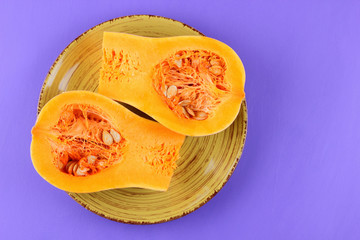 Halves of a pumpkin on a green plate, pumpkin on an ultraviolet background, vegetables pop art, minimalism, orange vegetables on a purple background, art, pumpkin for a designer, vegan