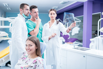 Fototapeta premium Dental medical team examining and working on young ¸female patient.Dentist's office, while technician is reviewing xray.
