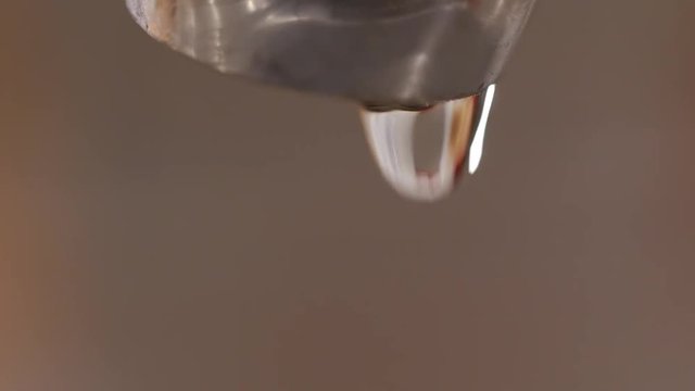 A macro of dripping kitchen faucet spout, water waste.