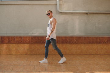 Young tattooed hipster man with sunglasses walking 