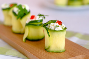 Rolls of zucchini stuffed with cheese and chives and red paprika.