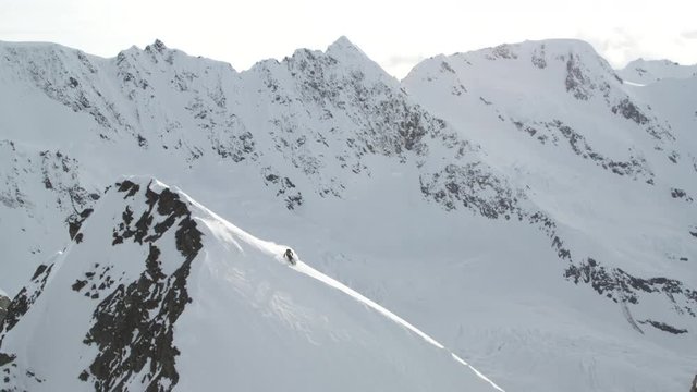 Slow motion aerial, skier on snowy mountainside