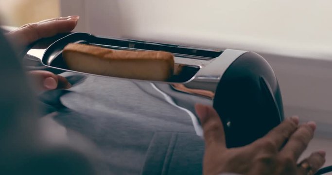 Hands put the bread in the toaster