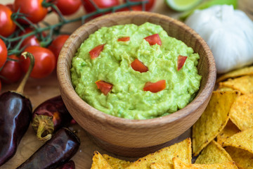 Guacamole in Wooden Bowl with Tortilla Chips and Ingredients