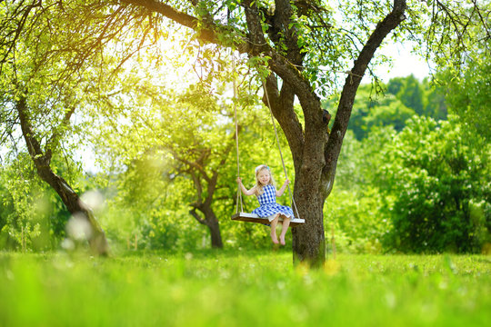 Cute little girl having fun on a playground outdoors in summer garden