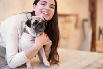 Young woman with cute pug dog at home. Pet adoption