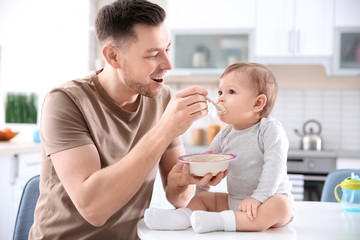 Obraz na płótnie Canvas Father feeding his little son in kitchen