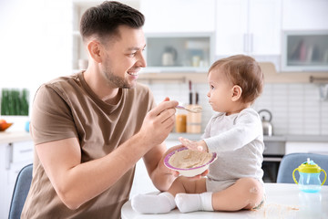Obraz na płótnie Canvas Father feeding his little son in kitchen