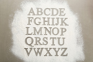 Silhouettes of alphabet letters on scattered flour