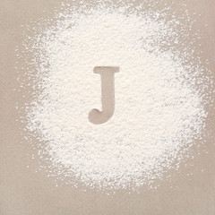 Silhouette of letter J on scattered flour