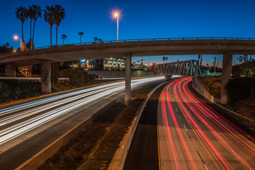 Dawn breaking the blue sky and vehicle headlights streak on both sides of interstate freeway.