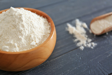 Bowl with flour on wooden table