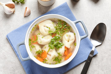 Ceramic pan of delicious soup with dumplings on table