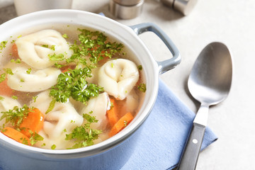 Ceramic pan of delicious soup with dumplings on table