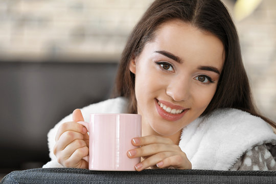 Smiling young woman with drink indoors
