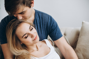 Fototapeta premium Gentle photo of a loving couple who hugs each other sitting on a sofa in a cozy bright room