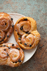 Fresh buns with raisins and icing on old rusty background. Top view