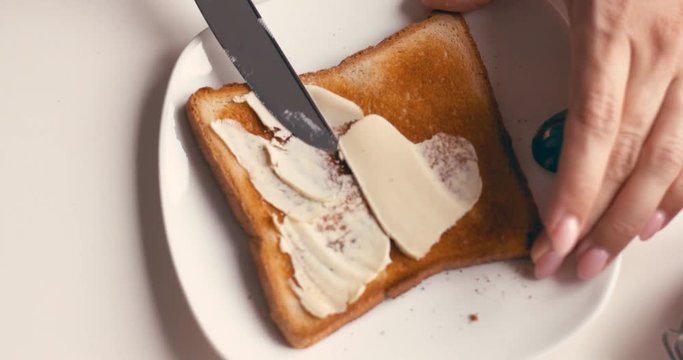 Hands of female spreading butter and jam on a slice of bread