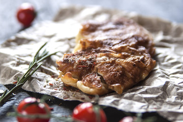 Grilled beef steak with rosemary and cherry tomatoes on a slate Board. Back light. Close up.