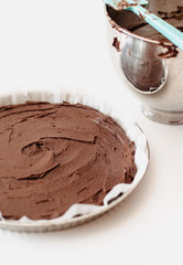 Glutenfree, flourless French Tarte au Chocolat or chocolate tarte made with chocolate, cocoa, butter, almond flour and sugar in tarte cake tin or cake pan before baking on white background
