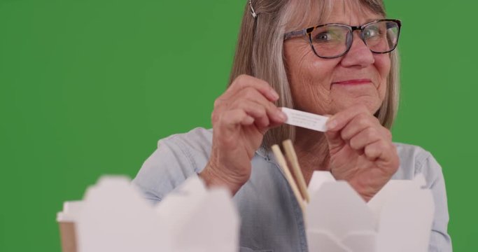 Portrait of joyful senior woman reading fortune on green screen