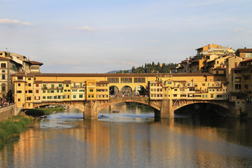 Naklejka premium River Arno and stone bridge with shops built along it, Ponte Vecchio (Old Bridge), during the sunset, Florence, Tuscany, Italy.