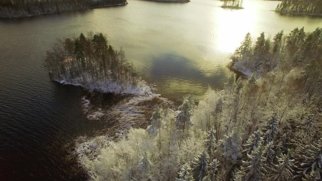 Small island and bay with first snow at a Nordic lake. Aerial shot.