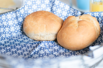 Traditional German Kaiser rolls or Austrian Vienna rolls homemade from yeast dough with white wheat flour in vintage bread basket with blue and white paper napkin on weekend breakfast table
