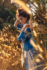 beautiful young woman on a field at sunset