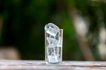 Ice in the glass and natural green background.Select focus blurred background.