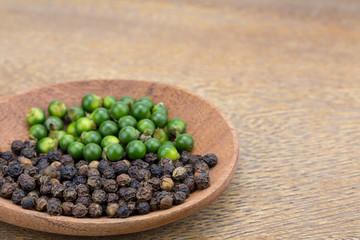 Fresh peppercorns and peppercorn in a wooden spoon. Put on a wooden cutting board Spices for cooking