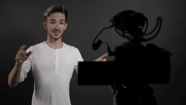 Young man vlog influencer talking to camera in home studio and recording video