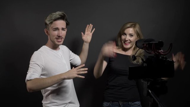 Excited smiling couple of young vloggers recording a new video in a professional studio
