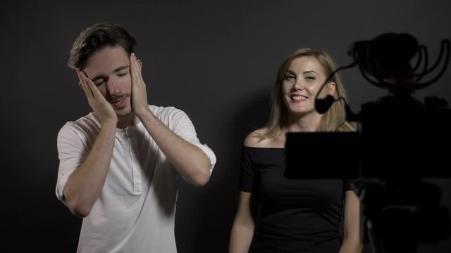 Young attractive man and woman recording video blog about latest trends on social media in a professional studio
