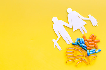 Prevention of diseases. Medicine for family health. Color pills near silhouette of family on yellow background top view space for text