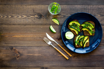 Idea for a healthy and nutritious breakfast. Plate with avocado toast with wholegrain bread on dark wooden background top view copy space