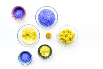 Colorful spa salt. Yellow spa salt with delicate spring flowers and violet lavender spa salt on white background top view copy space