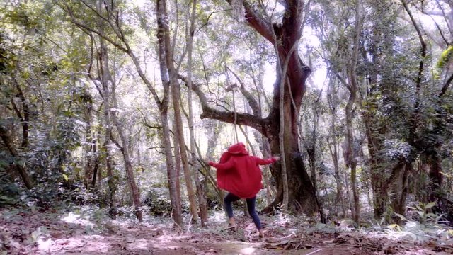 Girl wearing a red hood runs happily through the bamboo jungle in Colombia, Slow motion