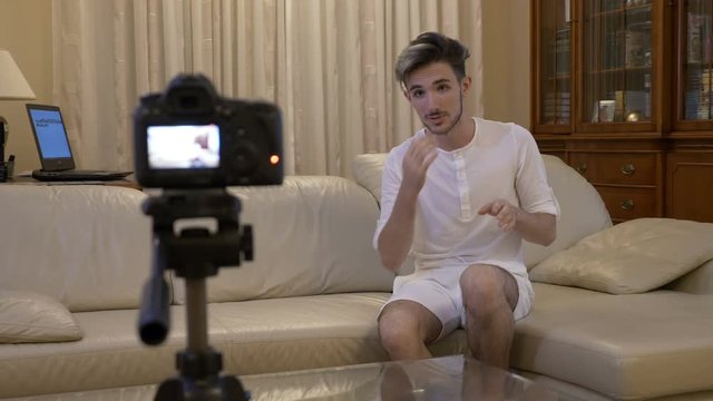 Male vlogger recording a video tutorial at home on couch about online business in social media