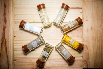 Concept of salt, black and white pepper powder accessories. Bottles with salt, black and white pepper on wooden background. Horizontal.