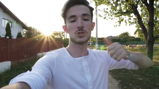 Teenager influencer boy recording a video with a camera held in hand walking and talking about his favorite outside activities in nature
