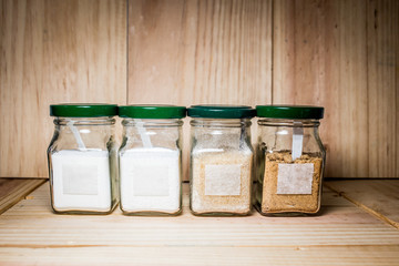Concept of salt, black and white pepper powder accessories. Bottles with salt, black and white pepper on wooden background. Horizontal.