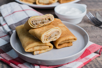 Russian Puncake Crepes stuffed with mushrooms and mozzarella on wooden table background.