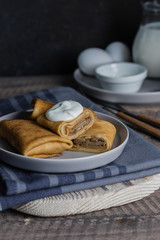 Russian Puncake Crepes stuffed with mushrooms and mozzarella on wooden table background.