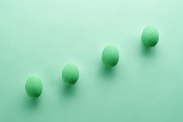 A pattern of Easter eggs on a pastel green background. Top view. Flat lay. Punchy pastels.