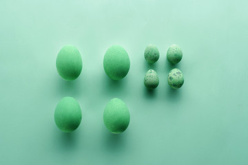A pattern of Easter eggs on a pastel green background. Top view. Flat lay. Punchy pastels.
