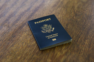 One blue American passport laying on a wooden desk